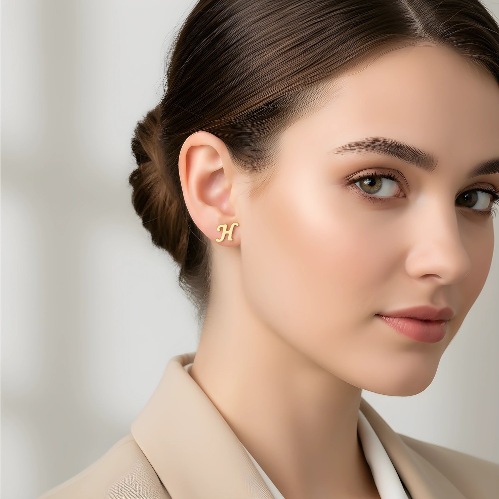 Pozłacane kolczyki litera H na uchu modelki - elegancka stylizacja biurowa