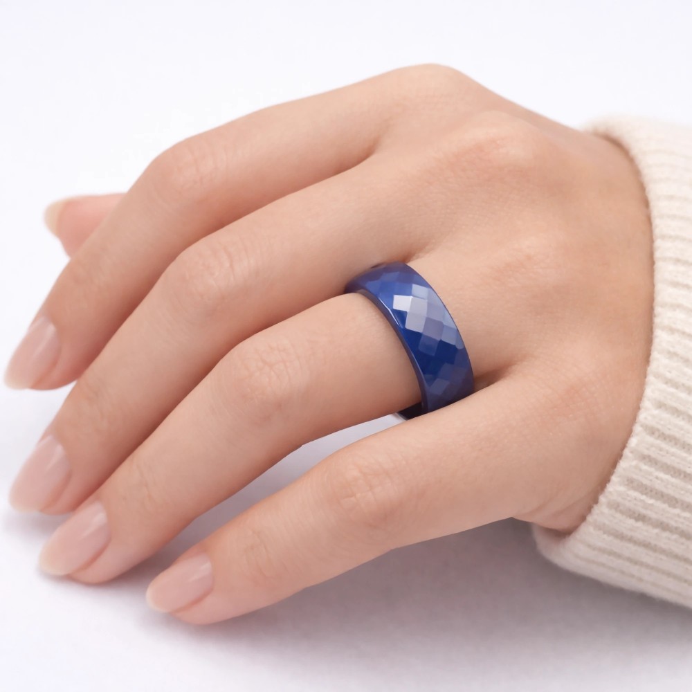 Niebieska fasetowana obrączka ceramiczna 6mm na palcu modelki, eleganckie ujęcie w białym swetrze