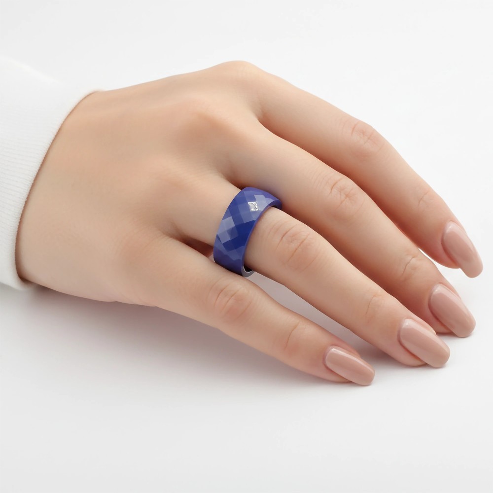 Niebieska fasetowana obrączka ceramiczna 6mm na palcu modelki, eleganckie ujęcie w białym mankiecie.