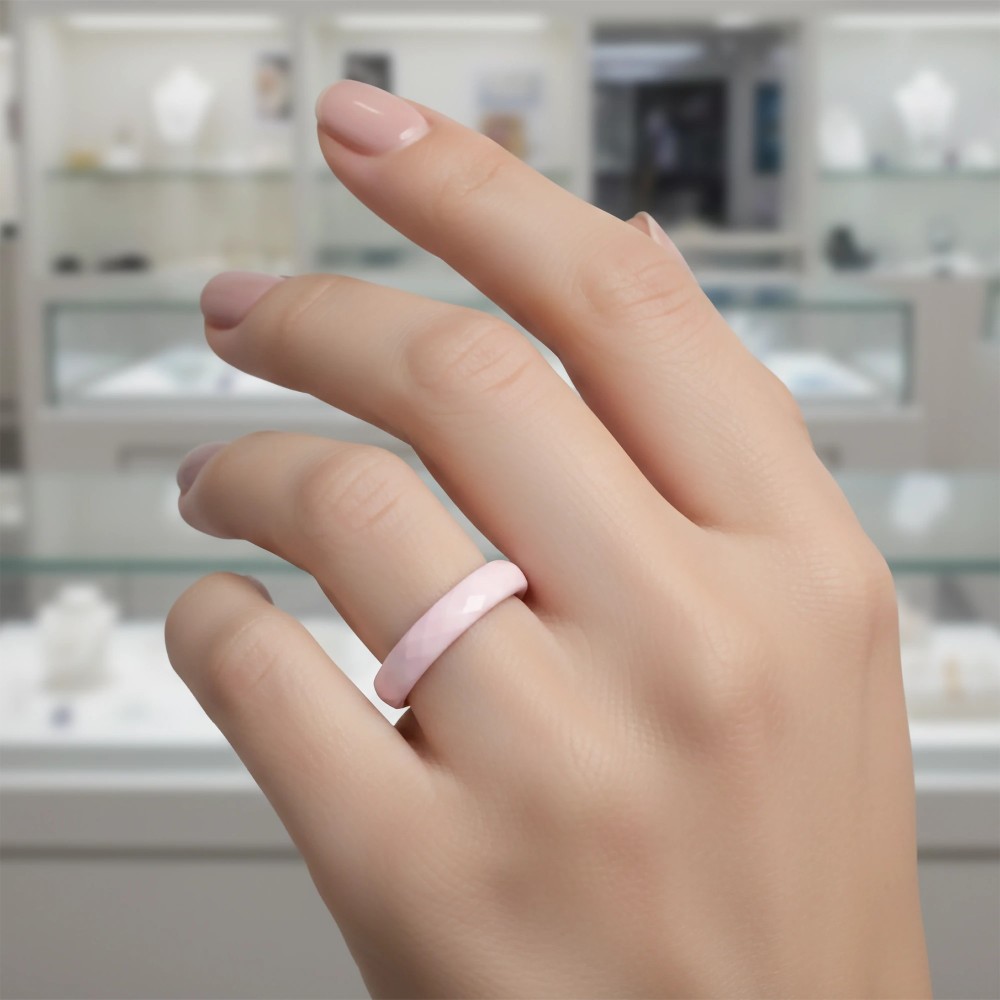 Zbliżenie na dłoń modelki z bladoróżową fasetowaną obrączką ceramiczną na palcu – zdjęcie produktowe.