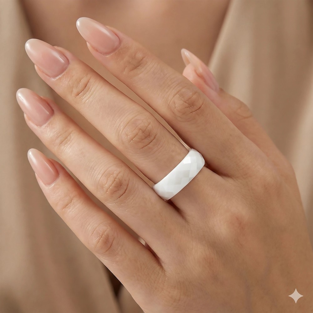 Elegancka dłoń modelki z zadbanym manikiurem prezentująca białą fasetowaną obrączkę ceramiczną 6 mm.