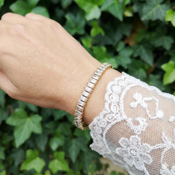 Błyszcząca złota bransoletka z białymi cyrkoniami na nadgarstku w koronkowej sukience